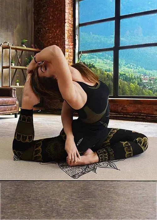 Vêtement yoga bio - yogini faisant du yoga dans un salon avec vu sur la nature | Achamana