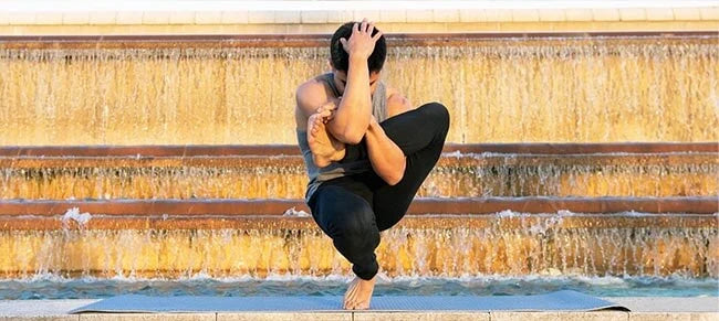 Vêtements yoga homme - Un yogi fait une posture e yoga dans la rue | Achamana